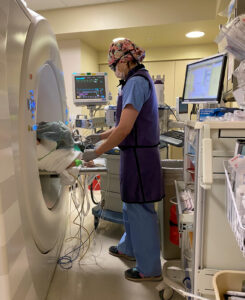 Figure 1. An anesthesiologist working in the CT suite, showing how the CT scanner impedes access to the patient and can make viewing the monitors and ventilator challenging.